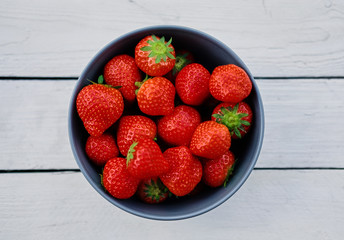 Delicious strawberry in a cup on a wooden desk.