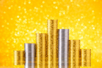 Gold and silver coins over shiny glitter bokeh with reflection