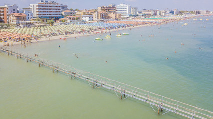 Dalla riviera romagnola vista aerea di ombrelloni colorati disposti in fila sulla spiaggia di...