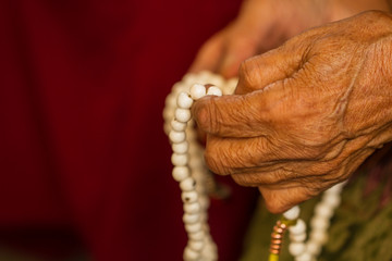The hands of an elderly woman with prayer bowls.
