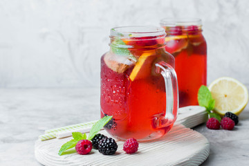 Summer Berry Drink. Lemonade with raspberry and blackberry with lemon, mint in mason jar on gray stone table background. Copy space, horizontal image