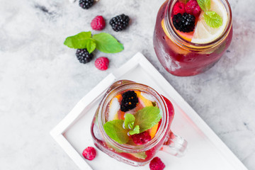 Summer Berry Drink. Lemonade with raspberry and blackberry with lemon, mint in mason jar on gray stone table background. Copy space, horizontal image