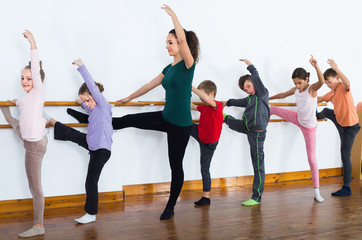 Fototapeta na wymiar glad boys and girls rehearsing ballet dance in studio