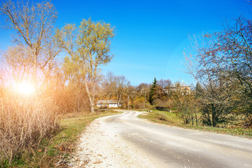 An autumn winding rural country road to the old hut located amid trees landing