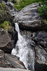 Obraz premium Wasserfall von Bergbach sprudelt zwischen Felsen und Gestein aus dem Berg ins Maggia Tal. Tessin, Schweiz