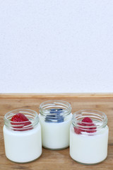 Three glass jars with yogurt and forest berries - vertical