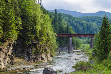 mountain river with a rapid current of rocks and a bridge