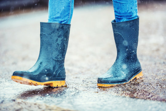 Girl in rubber boots outdoors in rainy day
