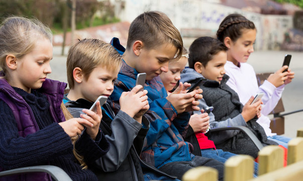 Kids sitting with mobile devices outdoor