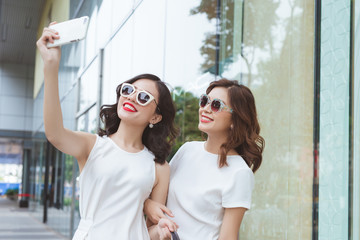 Two young girls go shopping together and take selfie photo by mobile phone