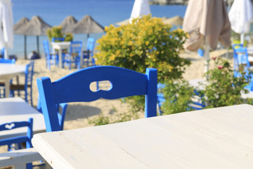 Fototapeta na wymiar White wooden picnic table by the sea in Greece, Empty picnic table for product display, Defocused beach in the background
