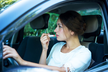 young girl puts lipstick while driving