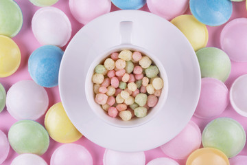 Small pastel color sweeties in a white cup.