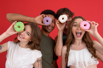 Young cheerful group of friends friends standing with donuts