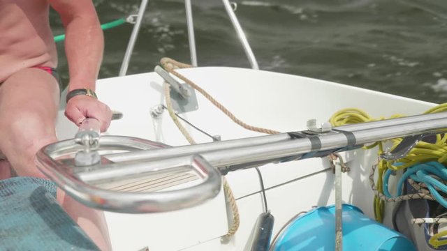 Sporty caucasian man drives a sailboat with tiller