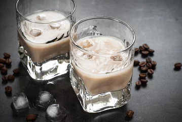 Cercles muraux Alcool Coffee liqueur in glasses with ice and coffee beans.
