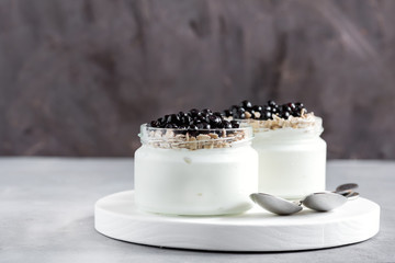 Healthy breakfast yogurt with blueberries and oat served in glass jar Spoons Napkin 