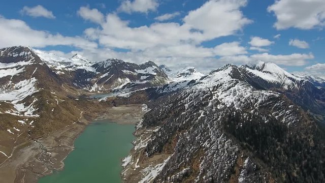 Aerial view on Ritom lake between snow-capped mountains at spring, Switzerland alps, 4k
