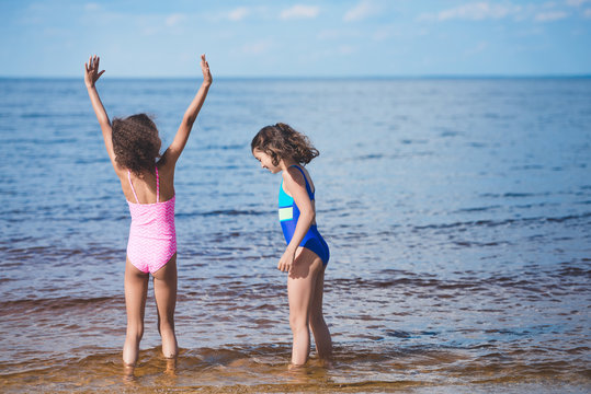 cute little girls in swimsuits playing at seaside together