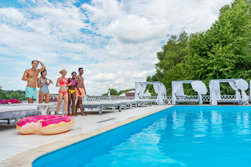 Happy multiethnic friends standing ready to jump into swimming pool