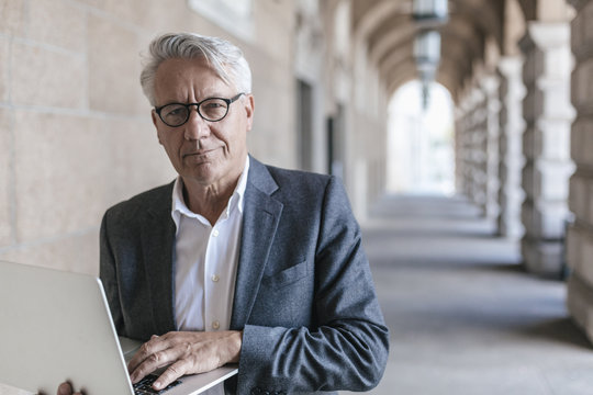 Portrait of senior businessman holding laptop
