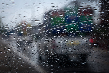 Rain droplets on auto glass with blurred exterior shots.