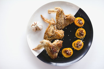 Home junk food - Frying Chicken wings with yellow tomatos om plate - top view