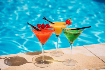 Colorful tropical cocktail with berries on edge of swimming pool