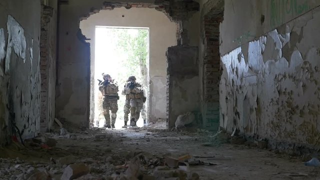 Slow motion of special infiltration unit walking to an entrance of an abandoned building searching enemy