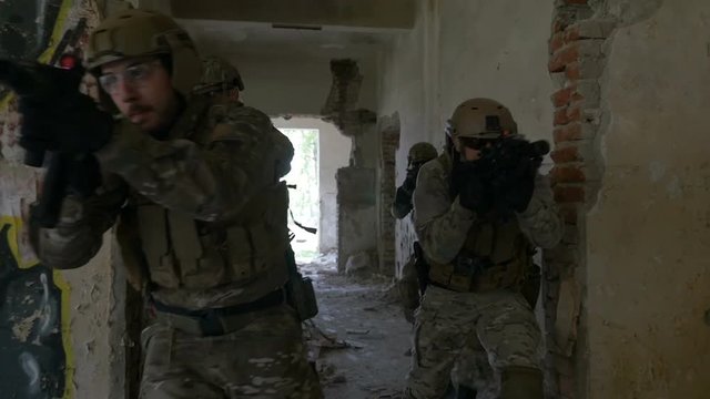 Slow motion of special forces army squad running and spreading through ruins of building in military exercise