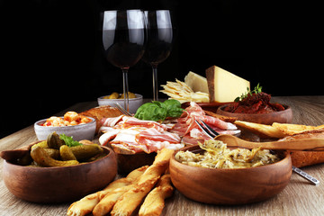 Italian antipasti wine snacks set. Cheese variety, Mediterranean olives, pickles, Prosciutto di Parma, tomatoes, artichokes and wine in glasses