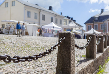 Naklejka premium City view of an old village with cobblestone roads. Metal chain as a fence where the focus point is.