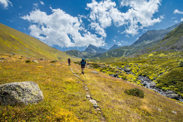 Fototapeta na wymiar Two unidentified hikers with large backpacks hiking on mountain Kackarlar. Kackar Mountains are a mountain range that rises above the Black Sea coast in eastern Turkey