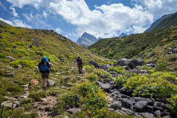 Fototapeta premium Two unidentified hikers with large backpacks hiking on mountain Kackarlar. Kackar Mountains are a mountain range that rises above the Black Sea coast in eastern Turkey
