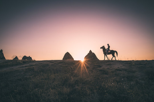 Man and horse silhouette on the background of valley at Cappadocia,Anatolia,Turkey.The great tourist attraction of Cappadocia best places to fly with hot air balloons.Rocks looking like mushrooms.