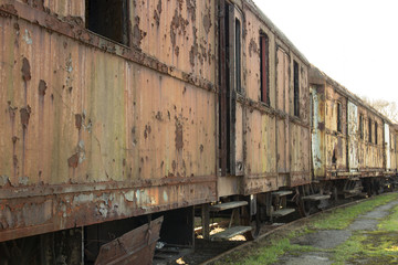 A row of many  old rusty carriages fastened together