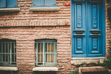 Fototapeta na wymiar ISTANBUL,TURKEY - May 6,2017:Facade view of vintage style old red brick wall house with blue door and turquoise window. Vintage building and old aged design in Balat,Istanbul,Turkey.