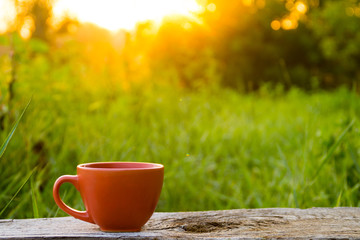 Morning cup of coffee on wooden table at sunrise