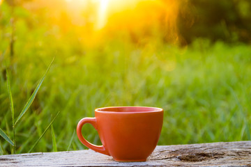 Morning cup of coffee on wooden table at sunrise