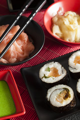 Sushi rolls, wasabi and ginger on red mat