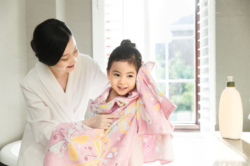 Mother and daughter wrapped in towel in bathroom