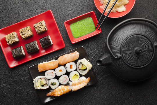 Sushi set and black teapot on black table