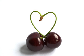 Closeup of cherries with a heart shaped stem on a white background