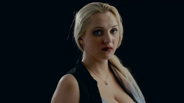 Sad Heavily Bruised Blonde Woman Looks Down and Then Into the Camera. Violence Theme. Shot on Isolated Black Background. Shot on RED EPIC-W 8K Helium Cinema Camera.