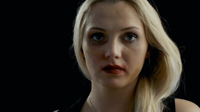 Close-up Shot Sad Heavily Bruised Blonde Woman Looks Down and Then Into the Camera. Violence Theme. Shot on Isolated Black Background. Shot on RED EPIC-W 8K Helium Cinema Camera.