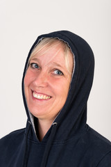 Beautiful european mid aged woman with blonde hair dressed in a black casual hooded jacket looking happy - studio shot in front of a white background