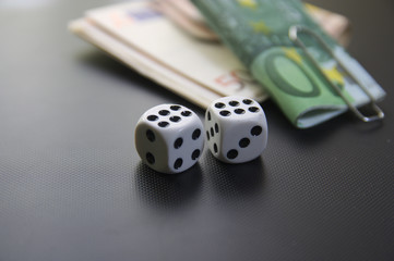 Two dice with bundles of money with black background. Side view