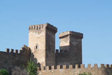 Old brown stone fortress with battlements on the background of the blue sky. Sudak, Crimea