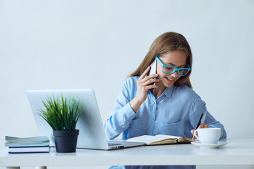 Young beautiful woman working at computer in office and calling by phone