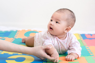 Mother playing with a little adorable infant baby girl on colorful eva foam indoors